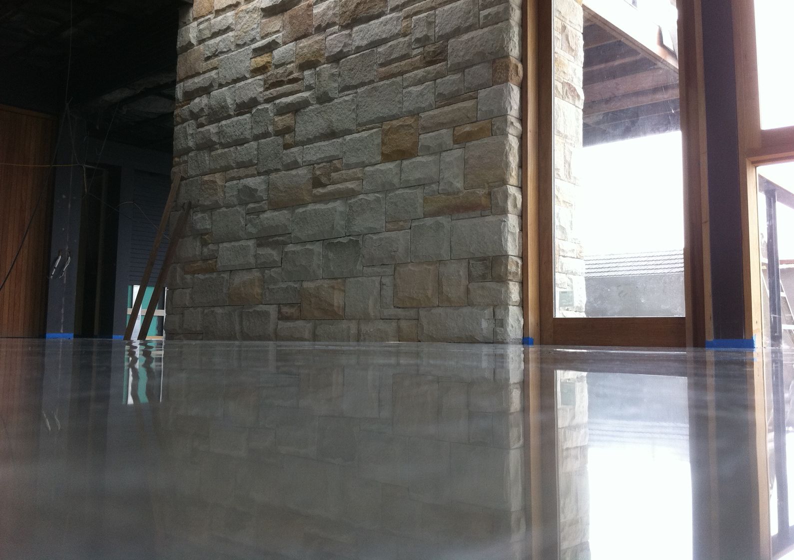 Fine Polished Concrete showing architectural sandstone wall and timber frame in reflection
